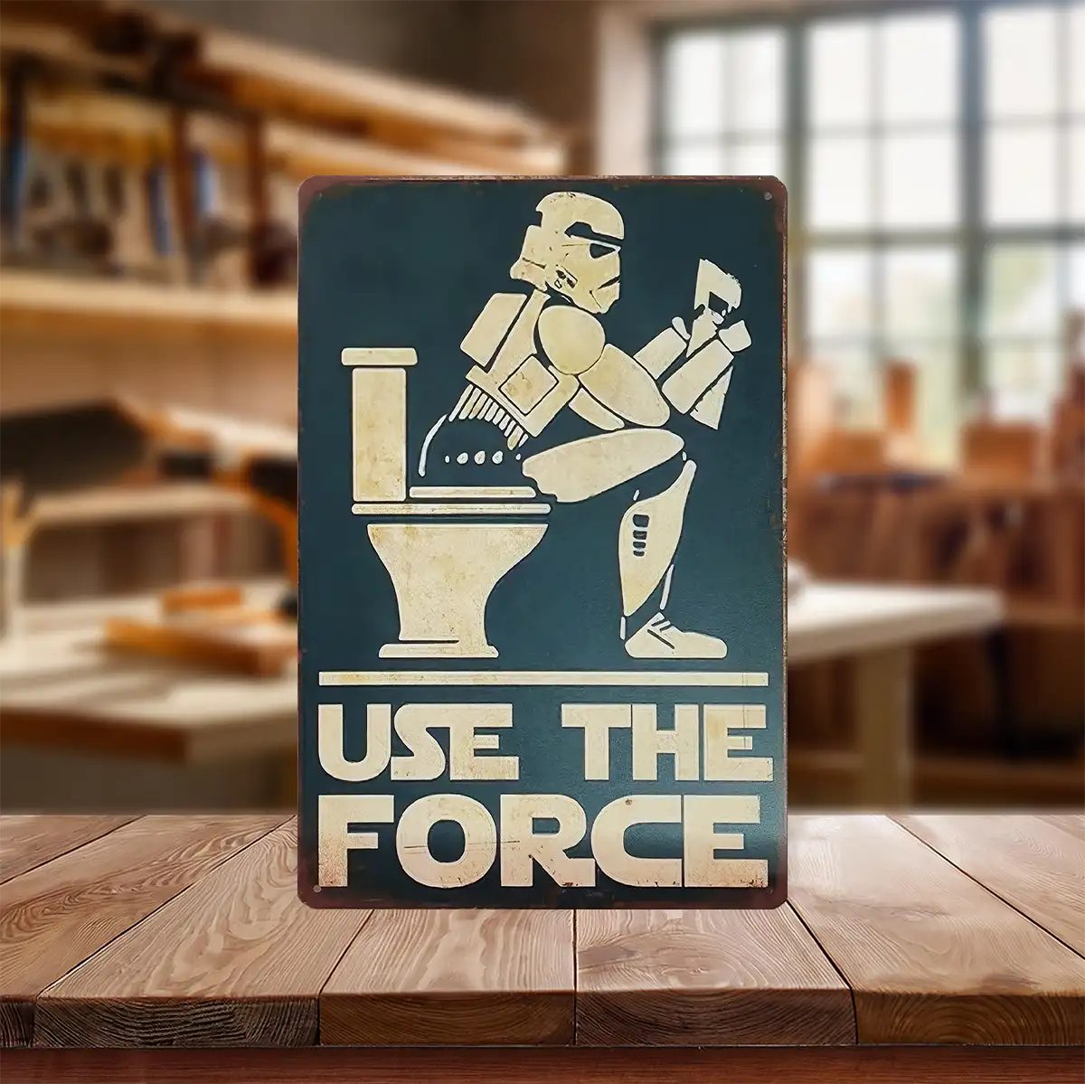 Metal sign of storm trooper sitting on toilet reading paper. Sign reads "use the force".